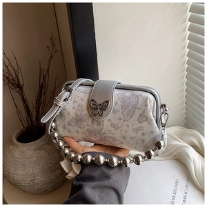 Detail of silver butterfly embroidery and modern metallic bead handle on fabric handbag