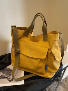Minimalist yellow canvas tote bag with olive green straps and silver metal buckle