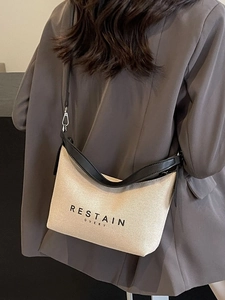 Sac hobo en toile crème avec finitions en PU noir porté par un mannequin