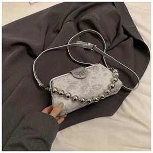 Close-up of silver butterfly embroidery and 3D metal buckle on lady's crossbody bag