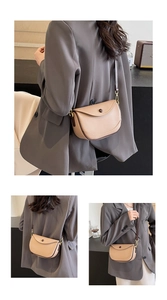 Detail view of beige lychee leather saddle bag with dark piping and gold hardware hooks