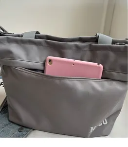 Detail of grey Oxford tote bag featuring a front zipper pocket with tablet storage space