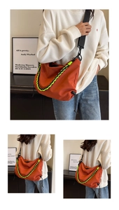 Detail of brick red nylon crossbody bag with contrasting neon green woven chain ornament