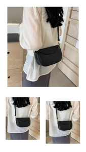 Detailed macro view of black lychee grain leather saddle bag with gold hardware