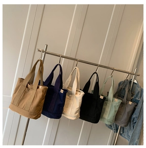 Detail view of large canvas tote bags in khaki, blue, cream, black, green, and gray colors