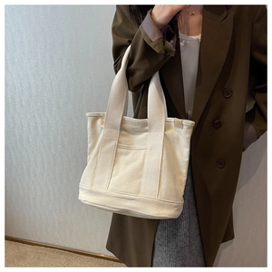 Close-up of cream canvas tote bag showing thick woven texture and front pocket detail