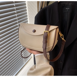 Close-up of lychee grain leather saddle bag with contrast trim and gold hardware detail