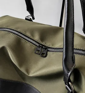 Detail shot of smooth black dual metal zippers on a durable army green nylon travel bag