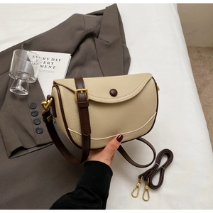 Detail of lychee textured saddle bag with dark brown trim and matte gold hardware