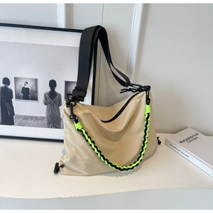 Detail of beige nylon shoulder bag showing green woven chain and black strap details