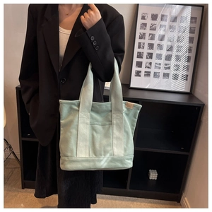 Detailed view of mint green canvas tote bag with side leather tag and front pocket