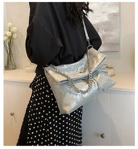 Silver metallic tote bag with chunky chain detail and butterfly logo shown on model