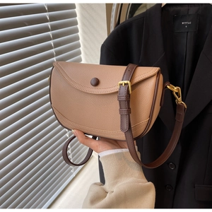 Detail of light brown saddle bag showing pebble grain leather texture and gold hardware