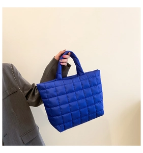 Detailed view of square quilted fabric and thick padded handle on a navy blue tote bag