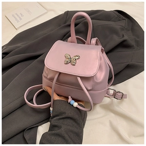 Detail eines rosa Mini-Rucksacks mit silberner Schmetterlingsschließe und Perlenverzierung