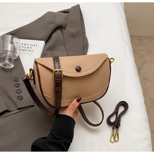 Detail of lychee textured saddle bag with dark coffee trim and golden hardware