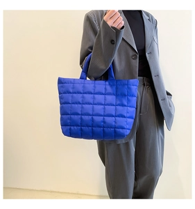 Close-up of vibrant blue quilted tote bag with padded nylon texture and square pattern
