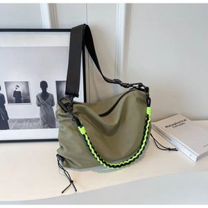 Detail of army green nylon shoulder bag with neon woven chain and black strap accents