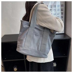 Grey-blue large canvas tote bag showing side view and outer pocket detail on model