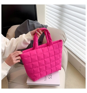 Detail of rose red quilted tote bag with checkered texture on a minimalist sofa