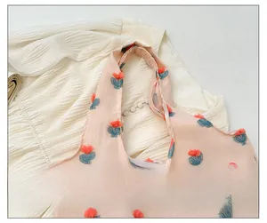 Detail of wide shoulder straps and textured tulip embroidery on pink tote bag