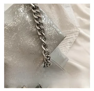 Detail shot of silver cracked texture leather and polished metallic chain on the tote bag