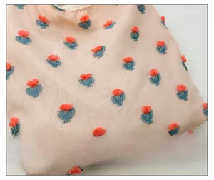 Detail of floral jacquard fabric with textured orange blossoms and soft pink textile