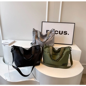 Detailed view of large Oxford cloth tote bags in grey, black, and olive green on a stand