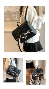 Close-up of black leather backpack with pink bows and elegant pleated texture
