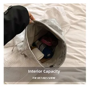 Internal capacity of silver metallic bucket bag showing folding umbrella and cosmetics