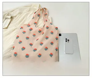 Detailed top view of pink floral tote bag with plush flowers and daily essentials