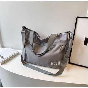 Detail of grey Oxford cloth tote bag with NOCO branding on a minimalist studio set