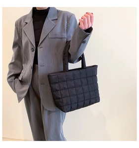 Detail of a black quilted tote bag with a soft padded texture and square pattern
