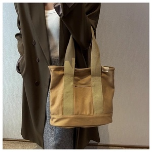 Detail of durable khaki canvas tote bag featuring functional front pocket and wide straps