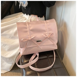 Close-up of pink satin backpack featuring elegant bow details and metallic plate