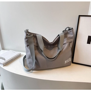Macro detail of grey oxford fabric tote bag featuring wide shoulder strap and NOCO logo