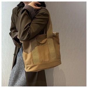 Close-up of brown canvas tote bag featuring reinforced webbing handles and front pocket