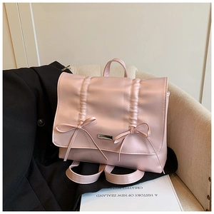 Detail of light pink bow backpack featuring pleated texture and elegant metal hardware