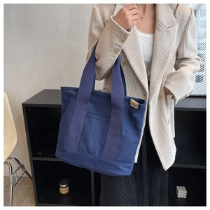 Detail of dark blue canvas tote bag with front pocket and reinforced handles