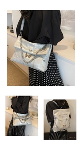 Detail of silver tote bag with gold butterfly accent and versatile chain straps
