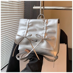 Close-up of silver metallic backpack featuring elegant bow knots and pleated texture