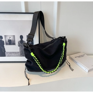 Detail of black nylon crossbody bag featuring neon green rope and side drawstring detail