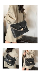 Detail of black tote bag with gold butterfly buckle and silver chain decoration