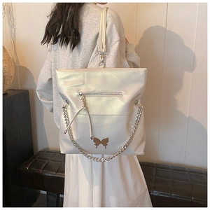 Detail of pearl white tote bag featuring metallic butterfly buckle and chunky silver chain
