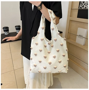 Lifestyle shot of white floral tote bag with pink embroidery on a shoulder strap