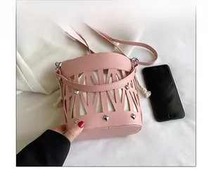 Pink hollow bucket bag with silver rivets compared to a smartphone for size perspective