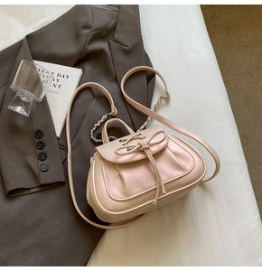Dettaglio borsa beige con fiocco, texture in pelle PU plissettata e tracolla a catena