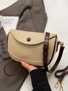 Minimalist beige pebble leather saddle bag with dark brown strap and gold metal hardware