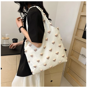 Detail of white canvas tote bag featuring 3D floral decorations and pink pom-pom accents