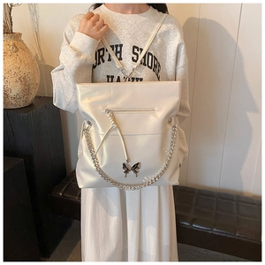 Detailed view of pearl white tote with metal butterfly charm and thick silver chain